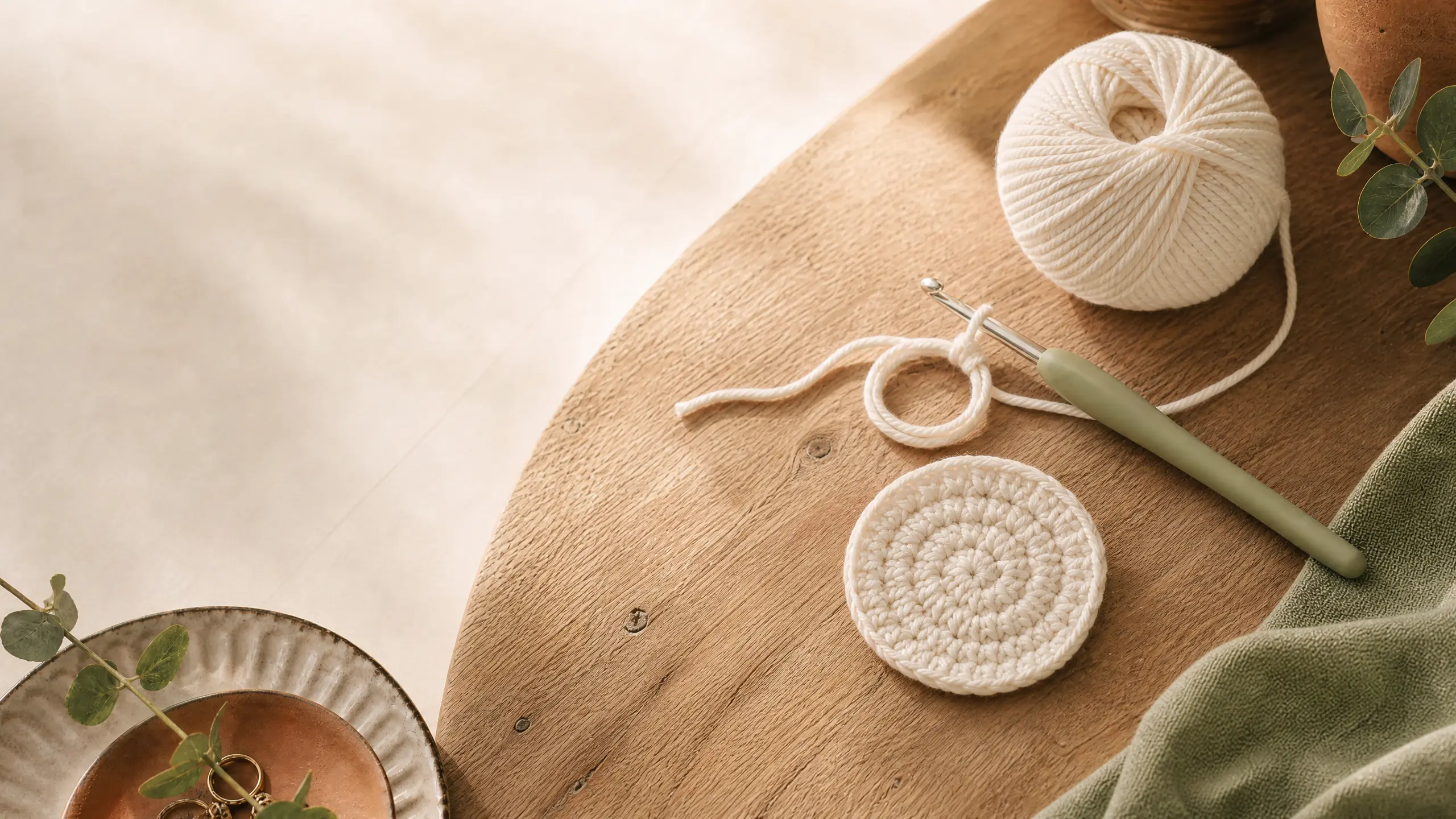 Crochet magic ring with yarn, hook and a small flat circle on a wooden table